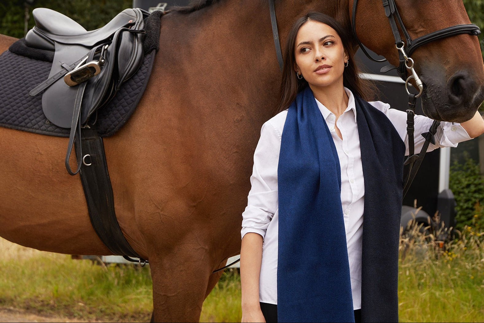 Woman standing next to a brown horse in an outdoor setting